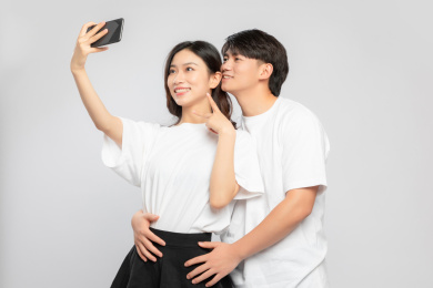  灰色背景里，正在自拍的亚洲年轻情侣