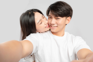 灰色背景里，正在自拍的亚洲年轻情侣