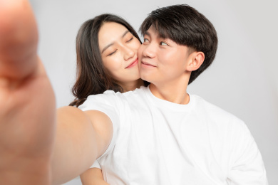 灰色背景里，正在自拍的亚洲年轻情侣
