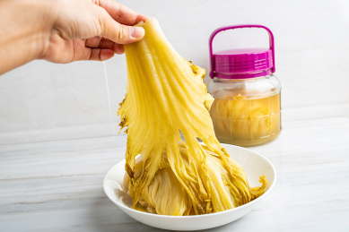 手拿一块腌制成金黄色的酸芥菜 