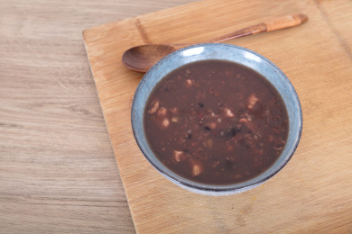 一碗盛好的腊八粥和一把木勺子在砧板上