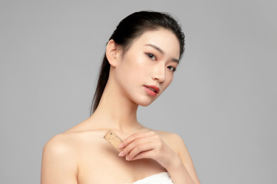  灰色背景里正在涂口红的亚洲美女面部特写，化妆护肤整容