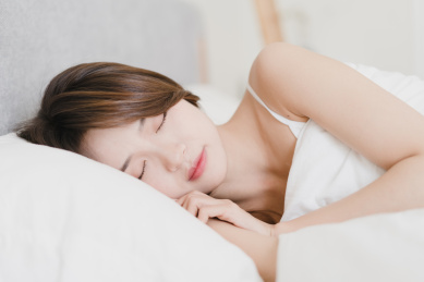 年轻的亚洲美女侧睡在白色的枕头上
