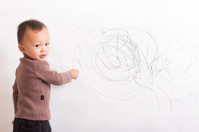天真可爱的孩童在白墙上涂鸦