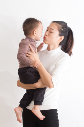 年轻的妈妈抱着亲吻可爱的小孩子