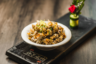 暗色木纹桌面上放着一份巧手浸花螺