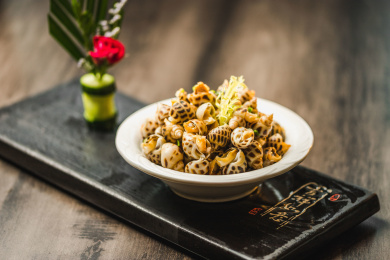 暗色木纹桌面上放着一份巧手浸花螺