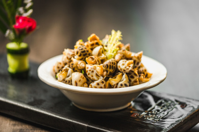 暗色木纹桌面上放着一份巧手浸花螺