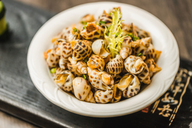 暗色木纹桌面上放着一份巧手浸花螺