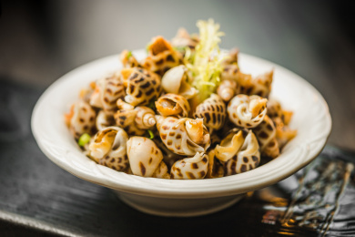 暗色木纹桌面上放着一份巧手浸花螺