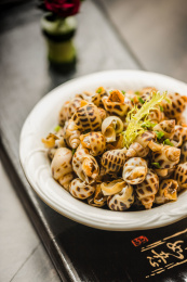 暗色木纹桌面上放着一份巧手浸花螺