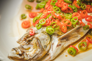  暗色木纹桌面上放着一份清蒸太湖白鱼