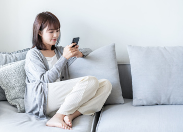 年轻女性侧坐在沙发上玩手机