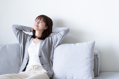 年轻女性闭眼靠在沙发上，双手自然交叠放在脑后