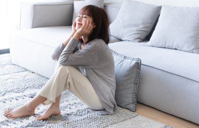 年轻女性双手托腮靠着沙发坐在地板上