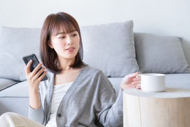 年轻女性一边玩手机一边拿起马克杯