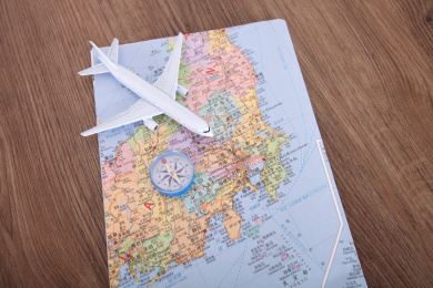 纸质日本旅行图上一个飞机模型和一个指南针