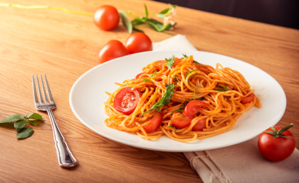 原木餐桌上白色盘子盛着一份美味的番茄酱意大利面