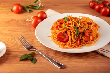 原木餐桌上白色盘子盛着一份美味的番茄酱意大利面