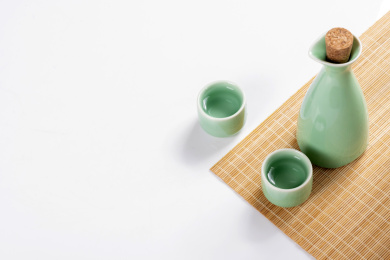 梅子青酒壶酒杯摆放在红色洒金背景上旁边放有中国结木托盘