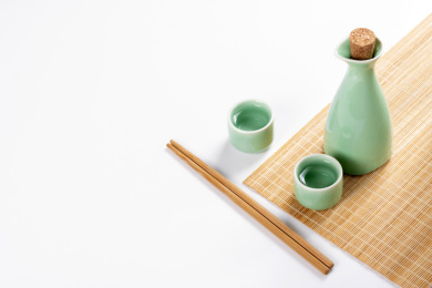 梅子青酒壶酒杯摆放在红色洒金背景上旁边放有中国结木托盘