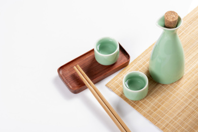 梅子青酒壶酒杯摆放在红色洒金背景上旁边放有中国结木托盘