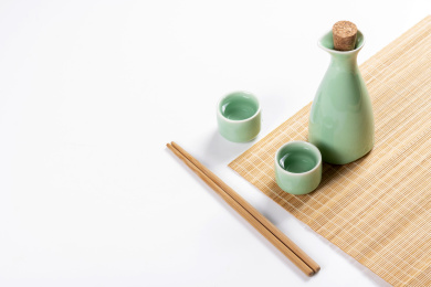 梅子青酒壶酒杯摆放在红色洒金背景上旁边放有中国结木托盘