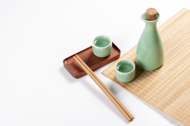 梅子青酒壶酒杯摆放在红色洒金背景上旁边放有中国结木托盘