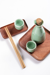 梅子青酒壶酒杯摆放在红色洒金背景上旁边放有中国结木托盘