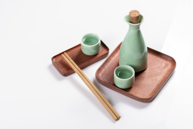 梅子青酒壶酒杯摆放在红色洒金背景上旁边放有中国结木托盘