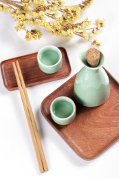 梅子青酒壶酒杯摆放在红色洒金背景上旁边放有中国结木托盘
