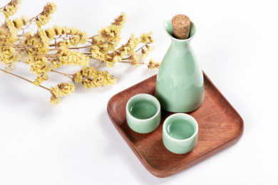 梅子青酒壶酒杯摆放在红色洒金背景上旁边放有中国结木托盘