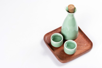 梅子青酒壶酒杯摆放在红色洒金背景上旁边放有中国结木托盘