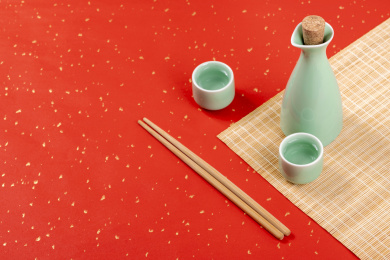 梅子青酒壶酒杯摆放在红色洒金背景上旁边放有中国结木托盘