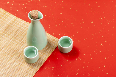 梅子青酒壶酒杯摆放在红色洒金背景上旁边放有中国结木托盘
