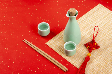 梅子青酒壶酒杯摆放在红色洒金背景上旁边放有中国结木托盘