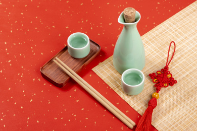 梅子青酒壶酒杯摆放在红色洒金背景上旁边放有中国结木托盘
