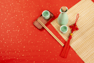 梅子青酒壶酒杯摆放在红色洒金背景上旁边放有中国结木托盘