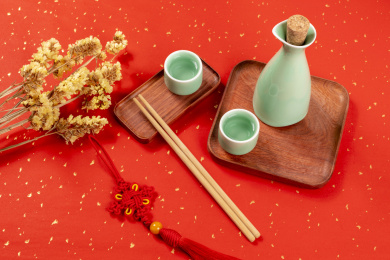 梅子青酒壶酒杯摆放在红色洒金背景上旁边放有中国结木托盘