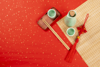 梅子青酒壶酒杯摆放在红色洒金背景上旁边放有中国结木托盘