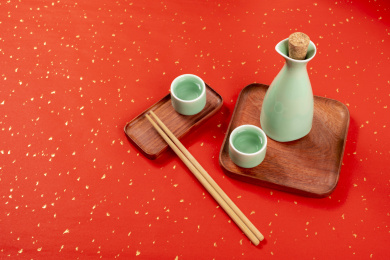 梅子青酒壶酒杯摆放在红色洒金背景上旁边放有中国结木托盘