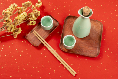 梅子青酒壶酒杯摆放在红色洒金背景上旁边放有中国结木托盘