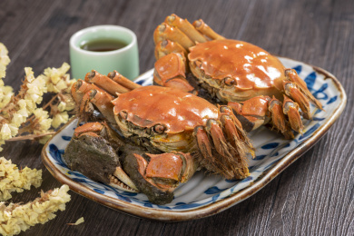味道鲜美的大闸蟹盛放在盘子中摆放在桌面上旁边放有酒壶酒杯