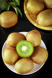 黑底上放着一盘猕猴桃和猕猴桃切面