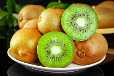 黑底上放着一盘猕猴桃和猕猴桃切面