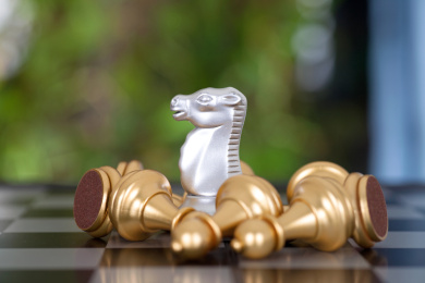 国际象棋棋盘上一枚被一堆金色兵棋子围绕的银色马棋子