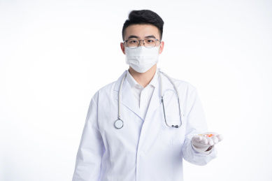 一位亚洲年轻男医生手里拿着水杯和药物