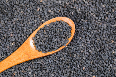 盛着黑芝麻的木勺放在平铺着黑色芝麻堆里