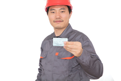 头戴红色安全帽手拿回家过年火车票的农民工