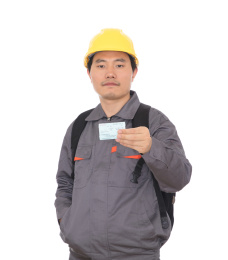 农民工背着书包头戴黄色安全帽手拿回家过年的火车票